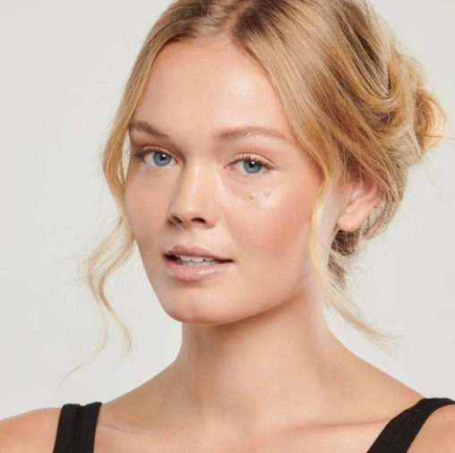 Woman with blonde hair and blue eyes against a plain background