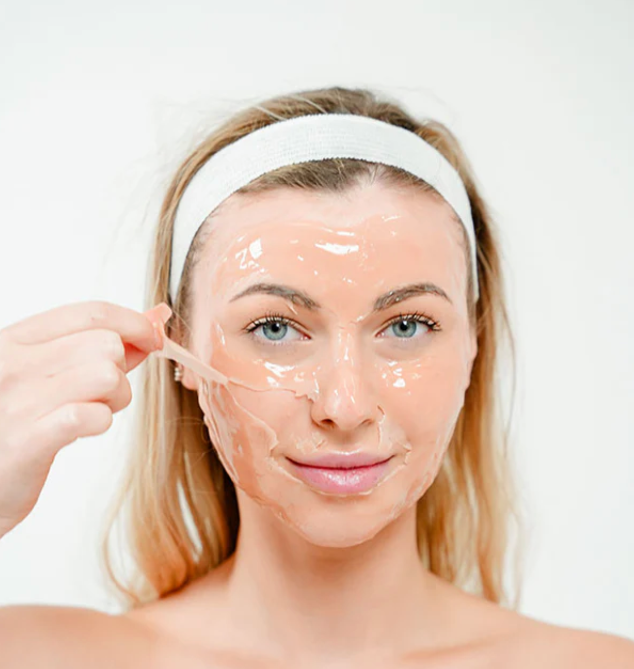 Woman applying a facial mask with a white background