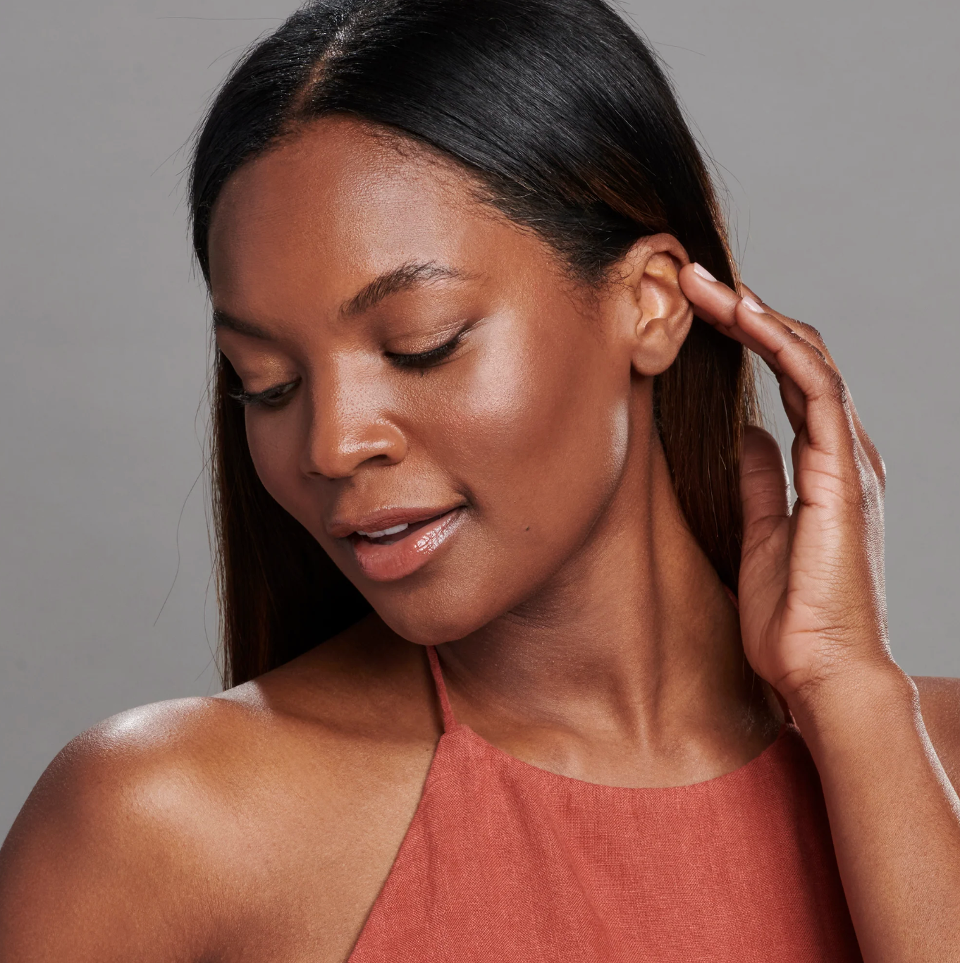Woman touching her ear against a neutral background