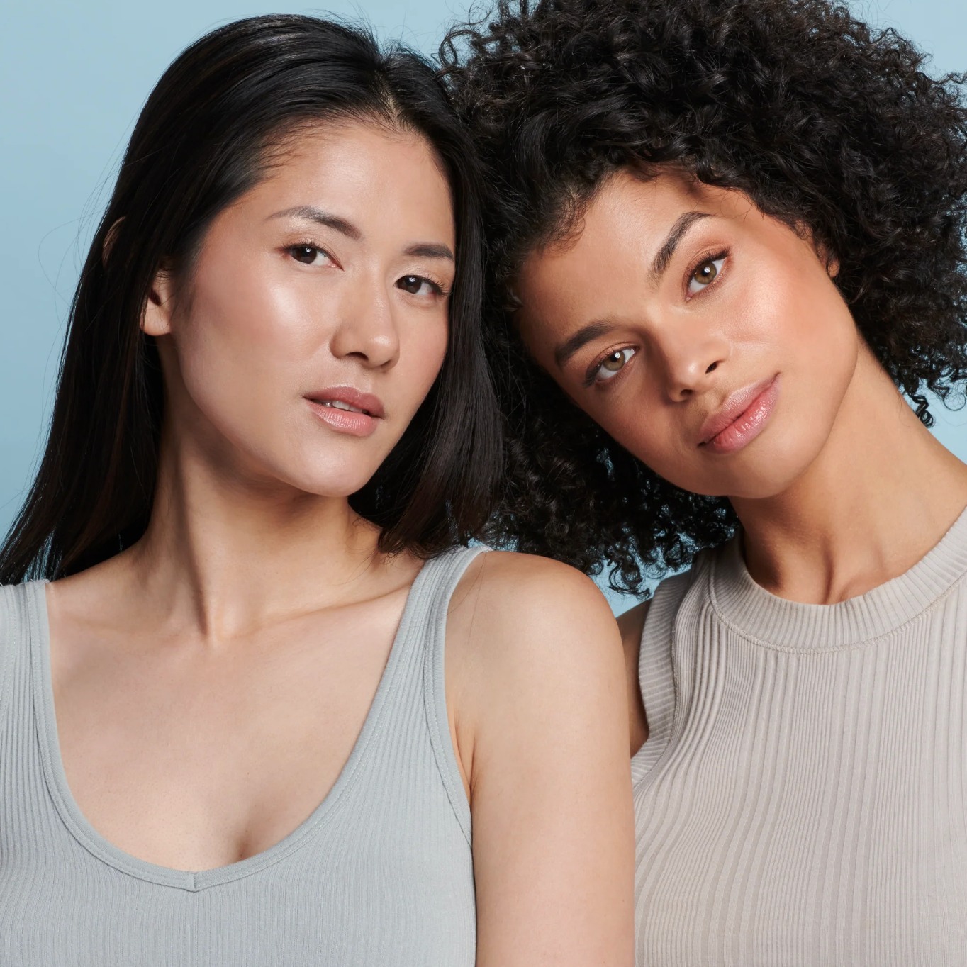 Two women with different hair types posing against a light blue background