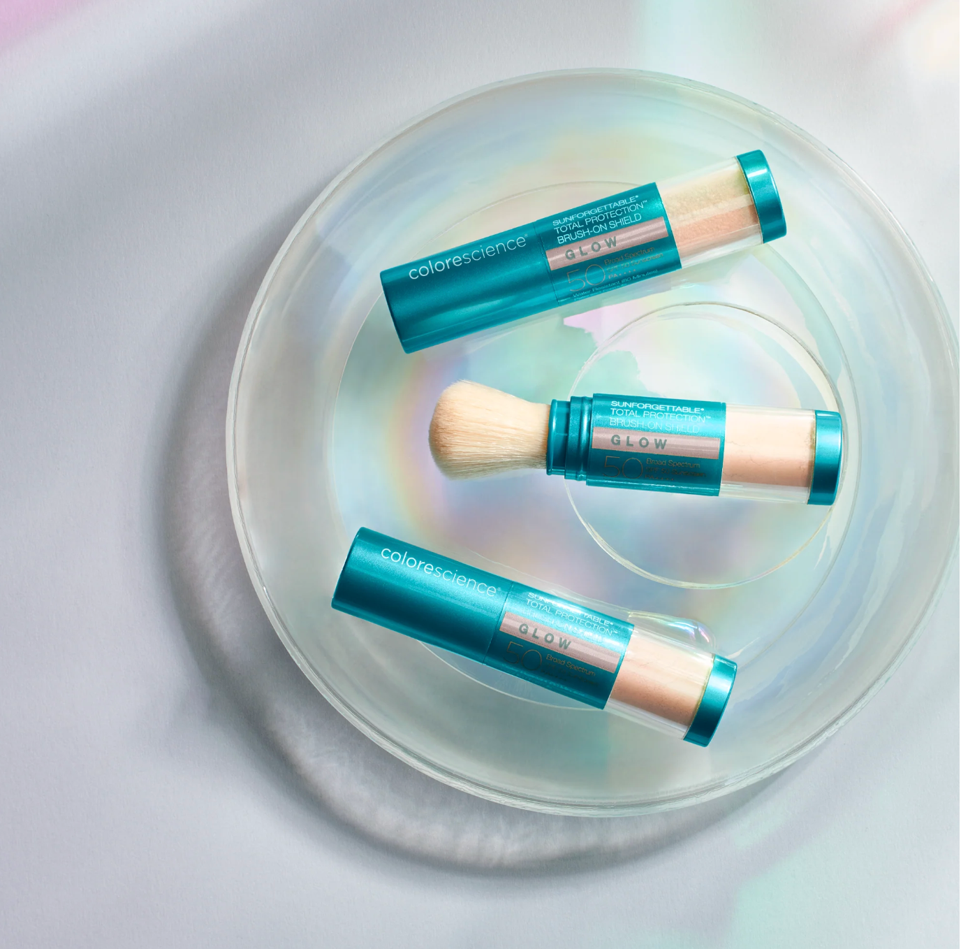 Three colorscience makeup products on a clear glass plate with a white background