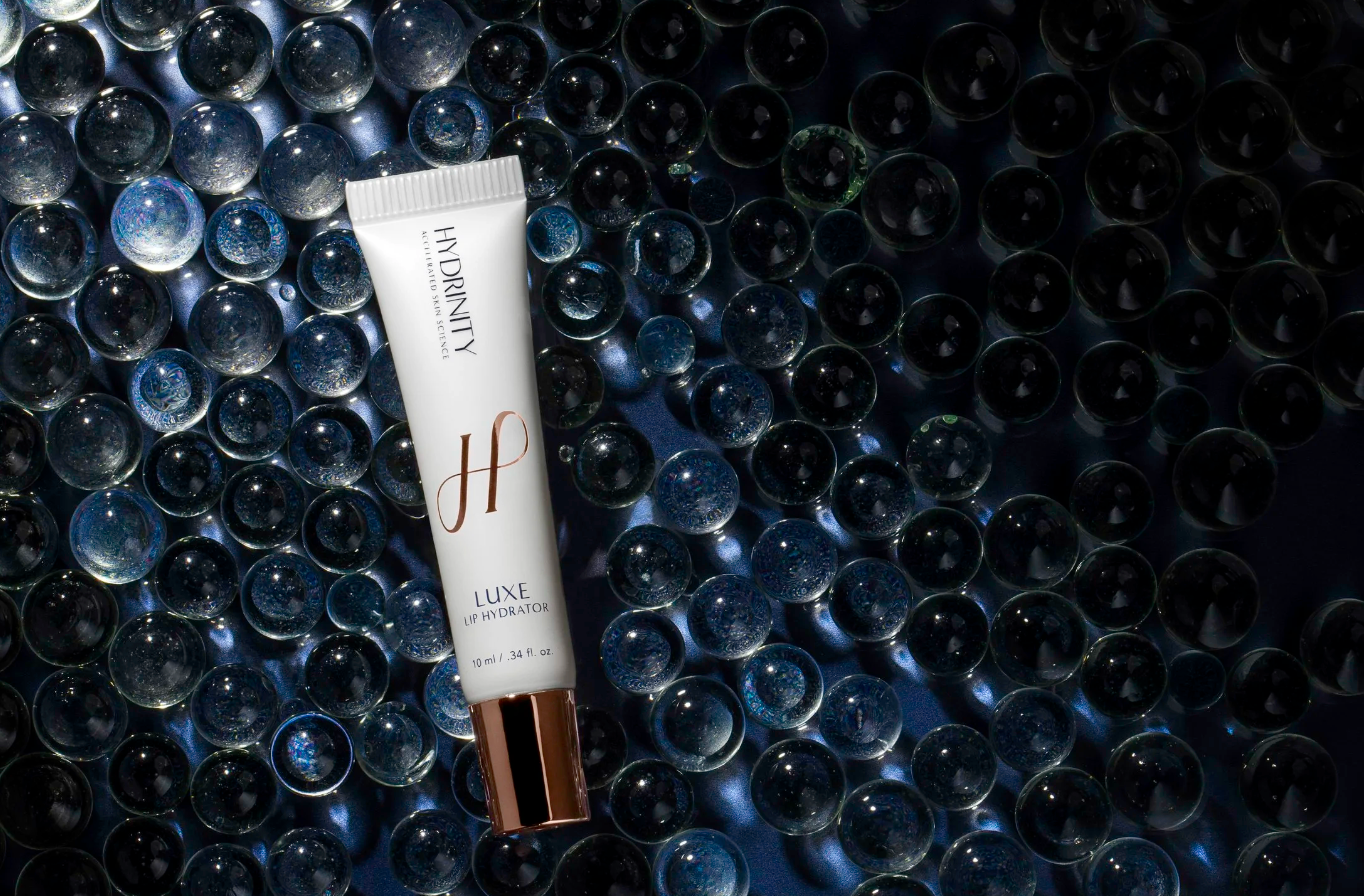 Tube of L'Hermitage skincare product on a textured dark surface with water droplets.