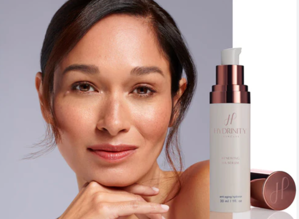 Woman with smooth skin next to a skincare product on a gray background