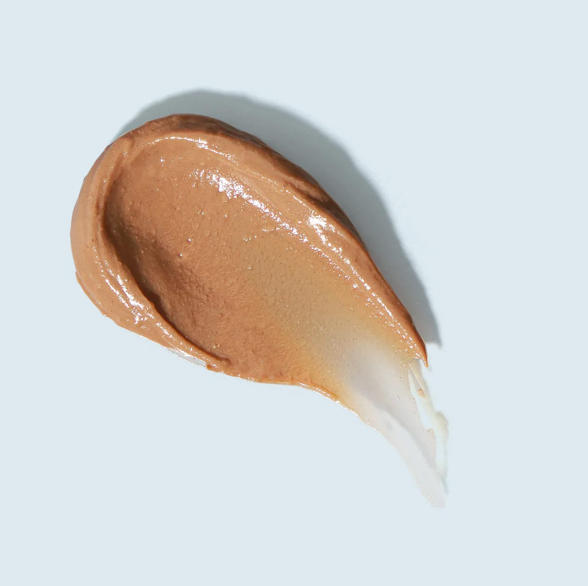 Brown cosmetic cream swatch on a light blue background